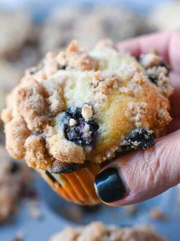 A blueberry muffin being held.
