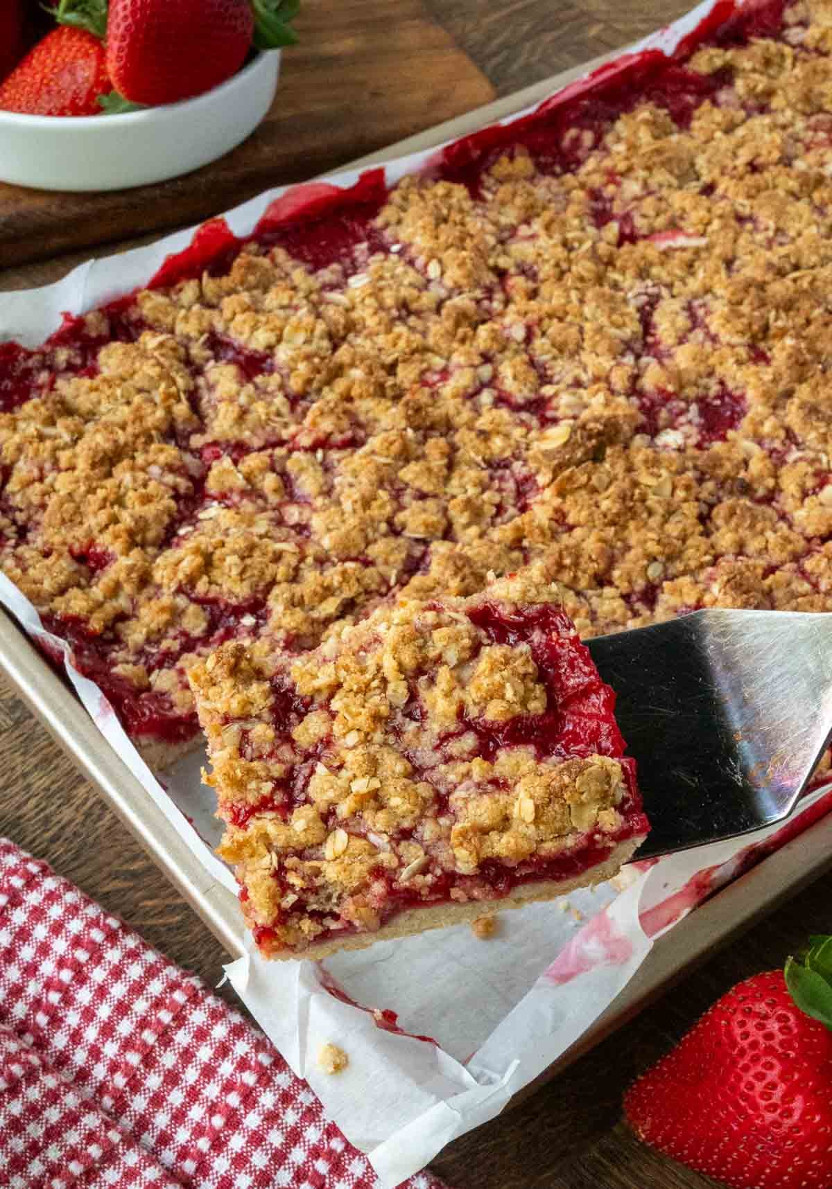 a spatula picking up a strawberry crumble bar.