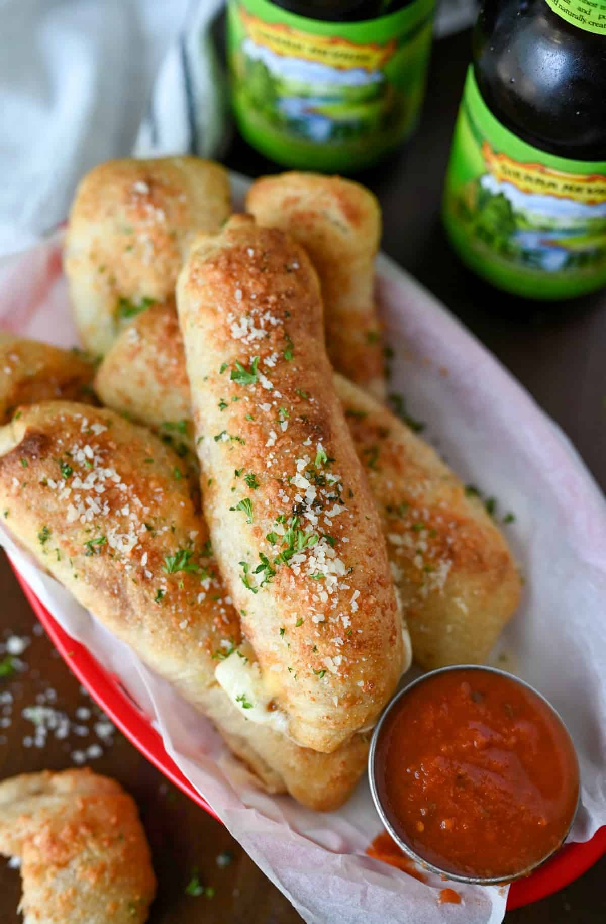 Pizza sticks in a basket with a side of pizza sauce.