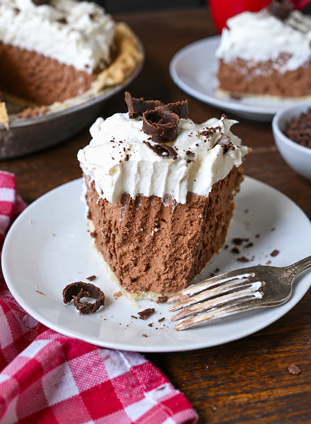 A slice of chocolate cream pie on a plate with a bite out of it.
