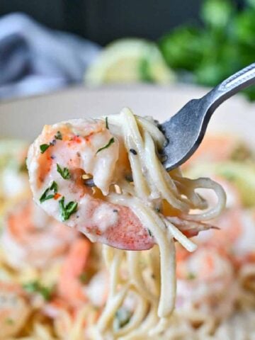 Shrimp and pasta being picked up with a fork.