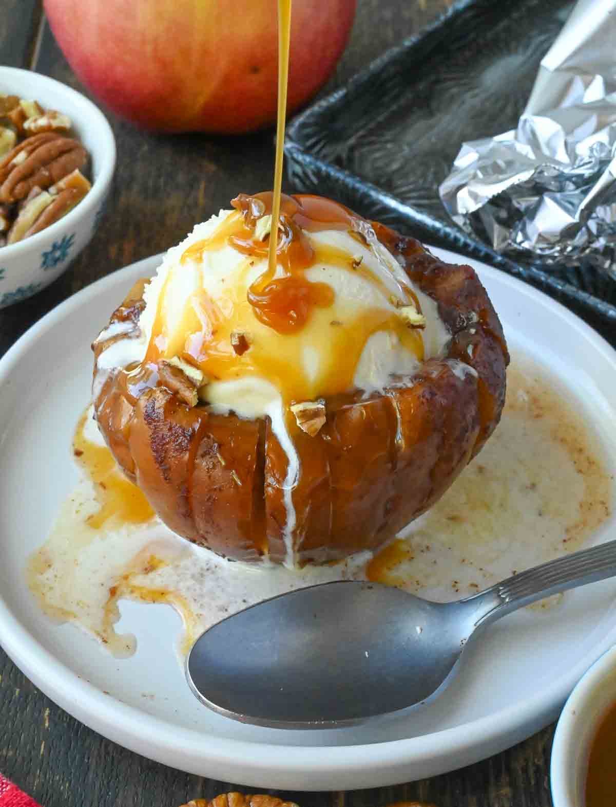 Caramel sauce drizzled on top of a grilled apple with ice cream.