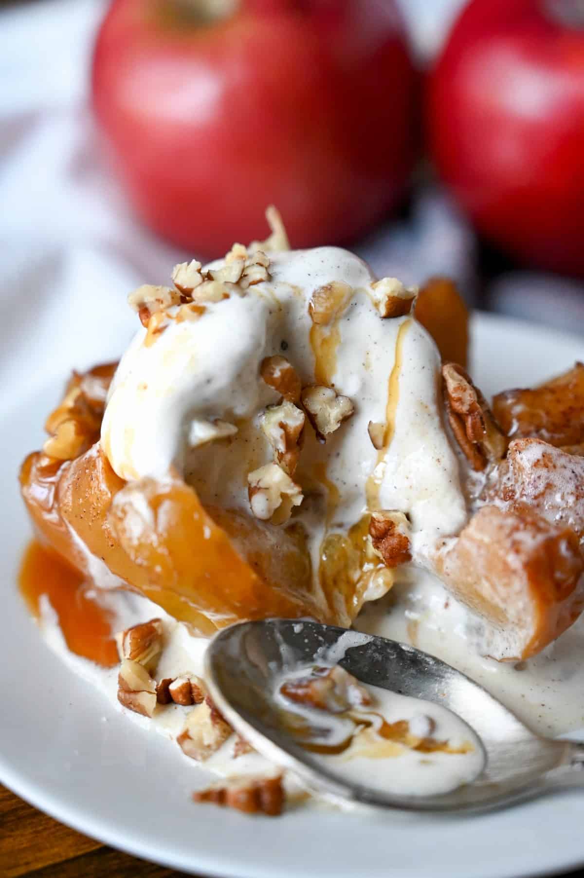 Close up photo of a bloomin grilled apple a spoon on a white plate.