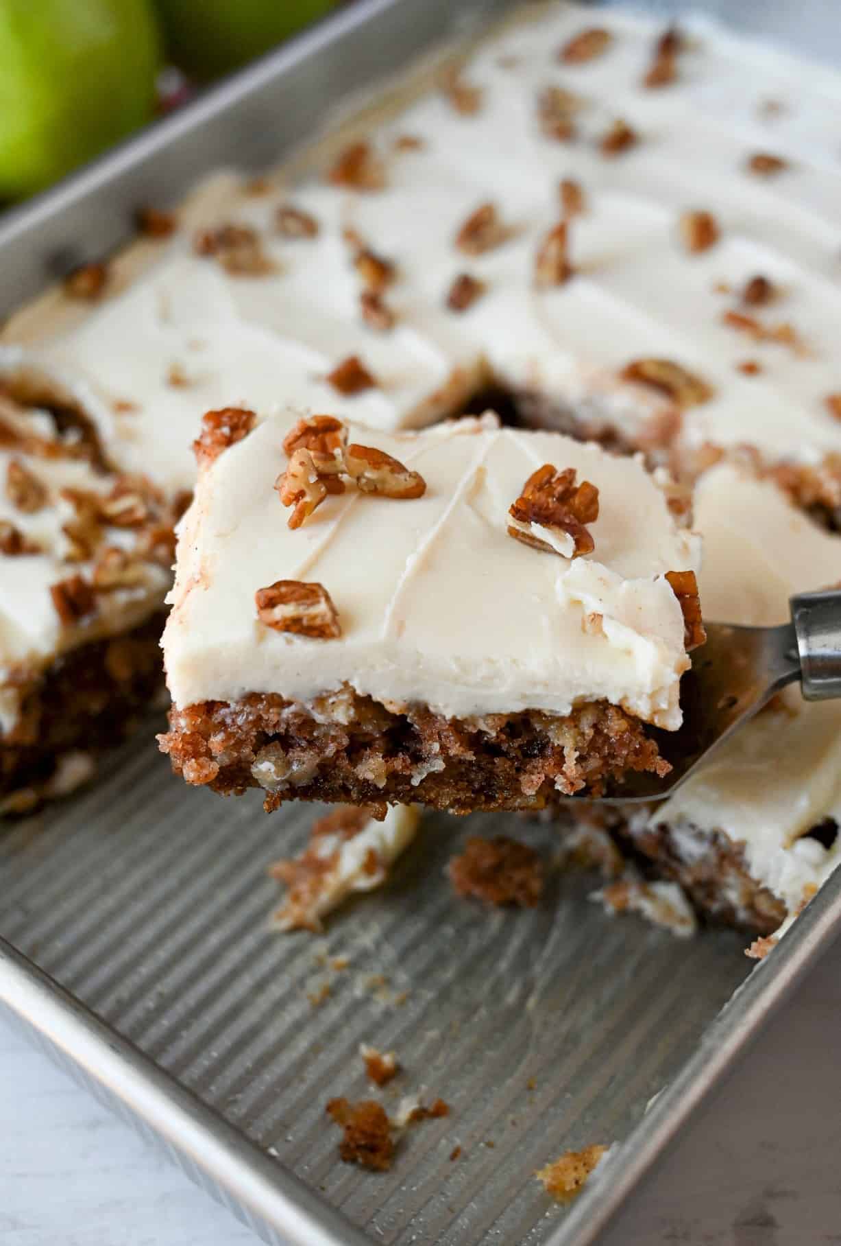 A piece of apple cake being removed from the baking pan with a spatula.