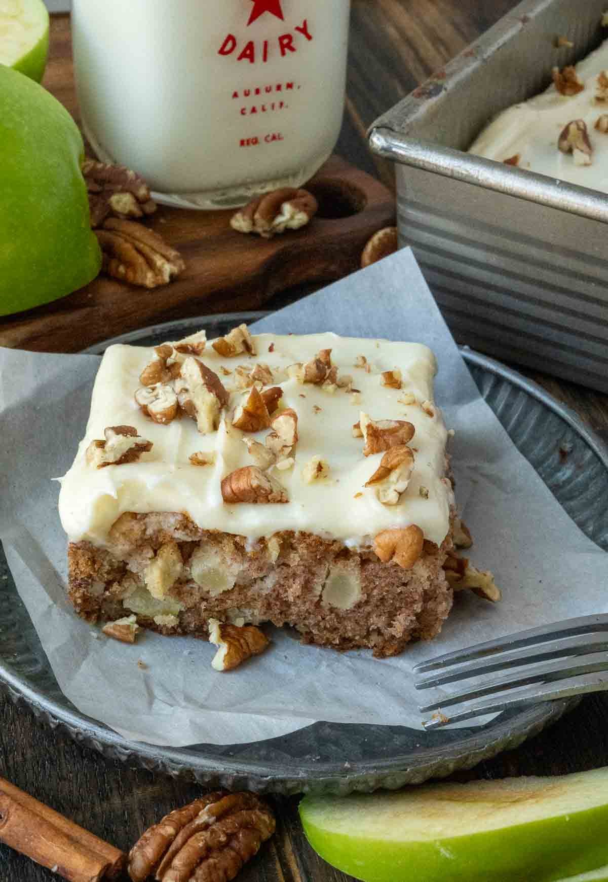 A piece of apple spice cake on a plate with a fork.