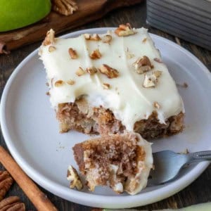 Apple cake on a plate with a fork taking a bite out.