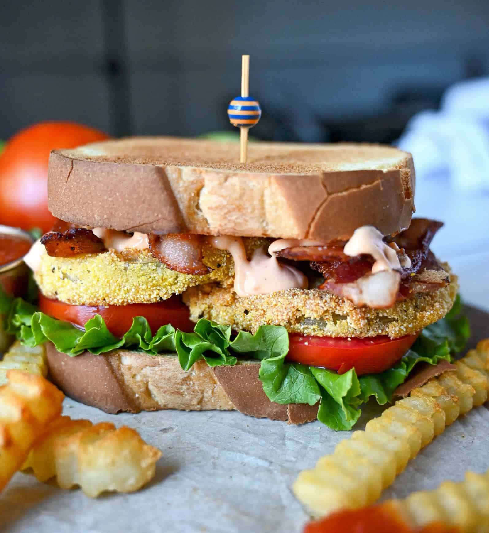 Fried green tomato BLT sandwich with special sauce. A side of crinkle cut french fries.