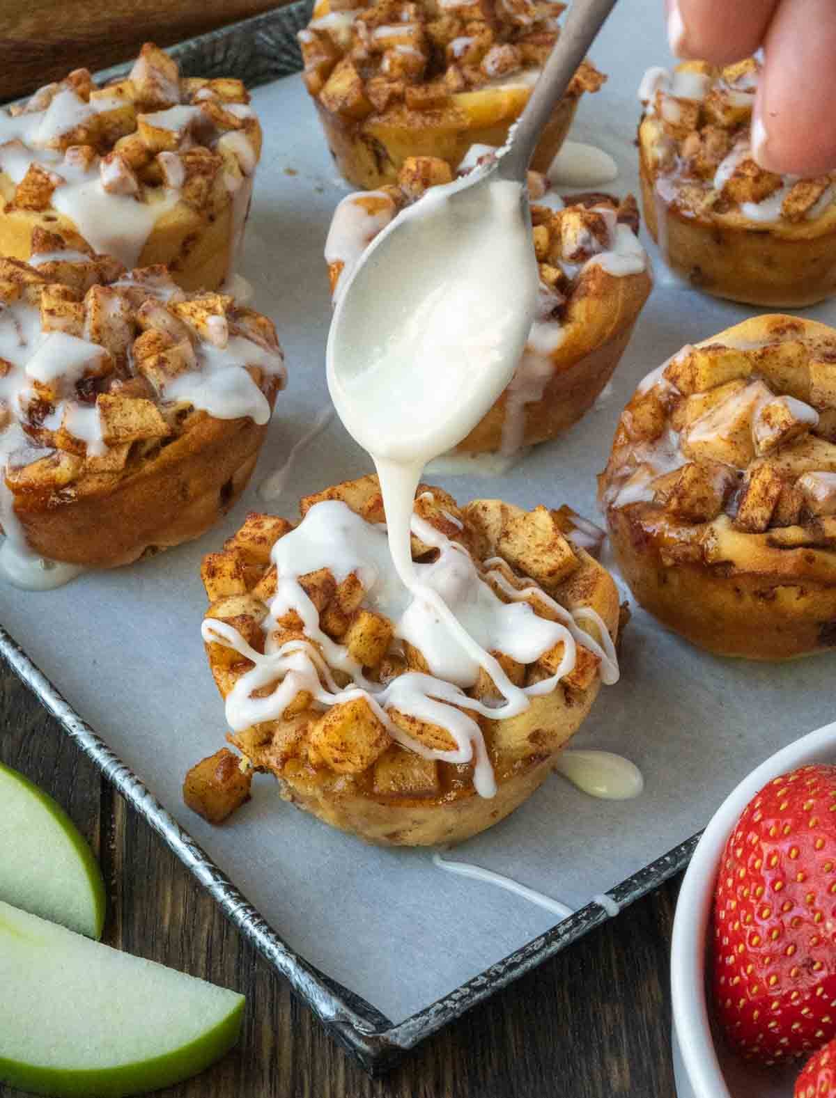 Glaze being drizzled over the apple muffins.