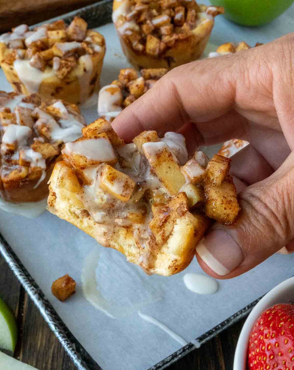 An apple cinnamon roll being picked up.