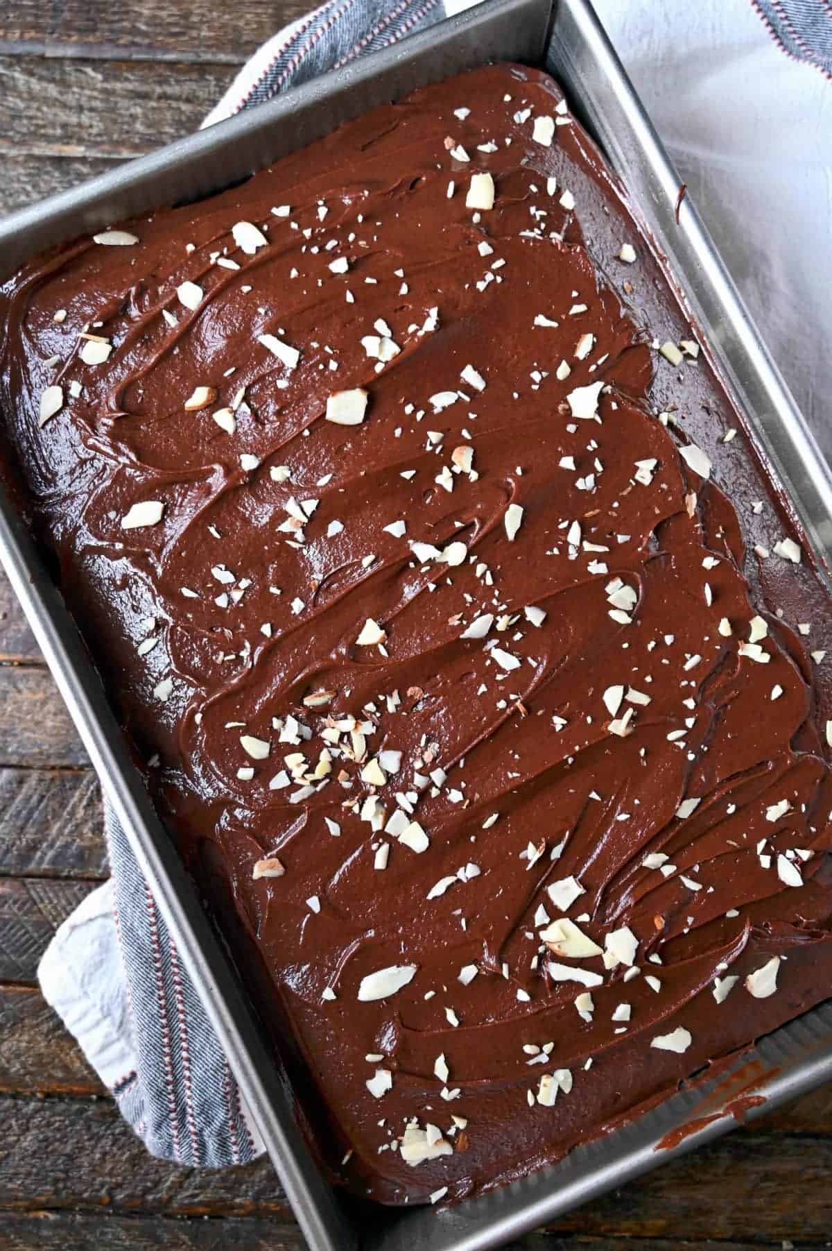 Chocolate mayonnaise cake in a 9x13 baking pan with chocolate frosting and slivered almonds on top.