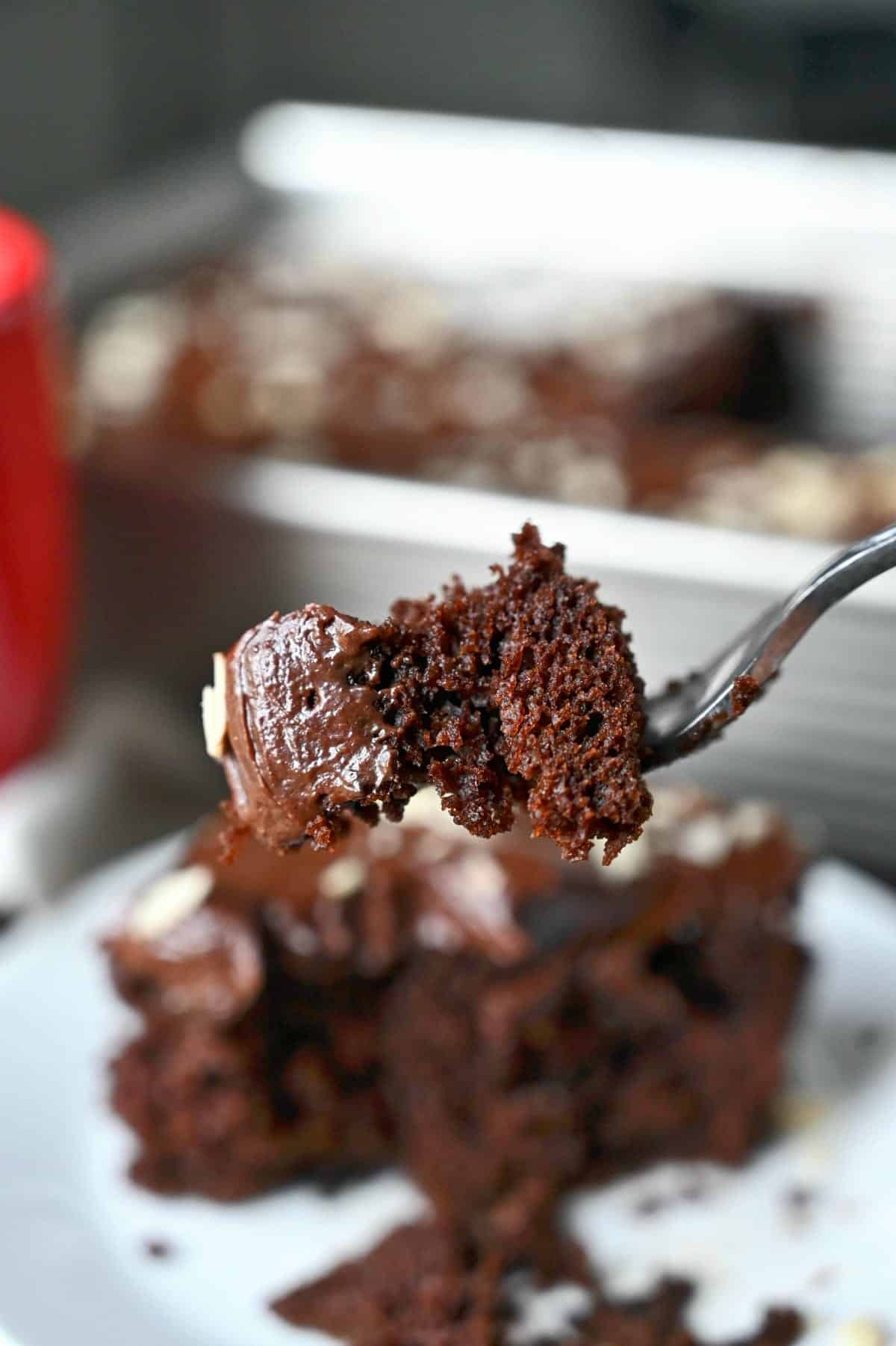 A bite of chocolate cake with ganache frosting on a fork.
