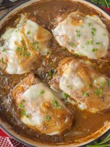 Pork chops in a skillet smothered in a french onion gravy.