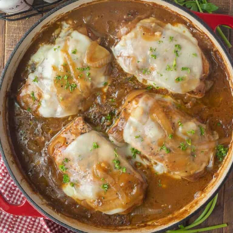 Pork chops in a skillet smothered in a french onion gravy.