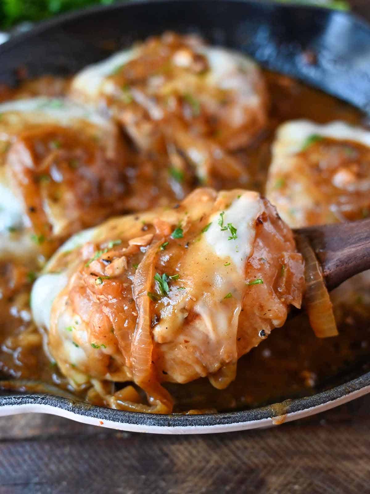 Pork chops in a skillet smothered in a french onion gravy.