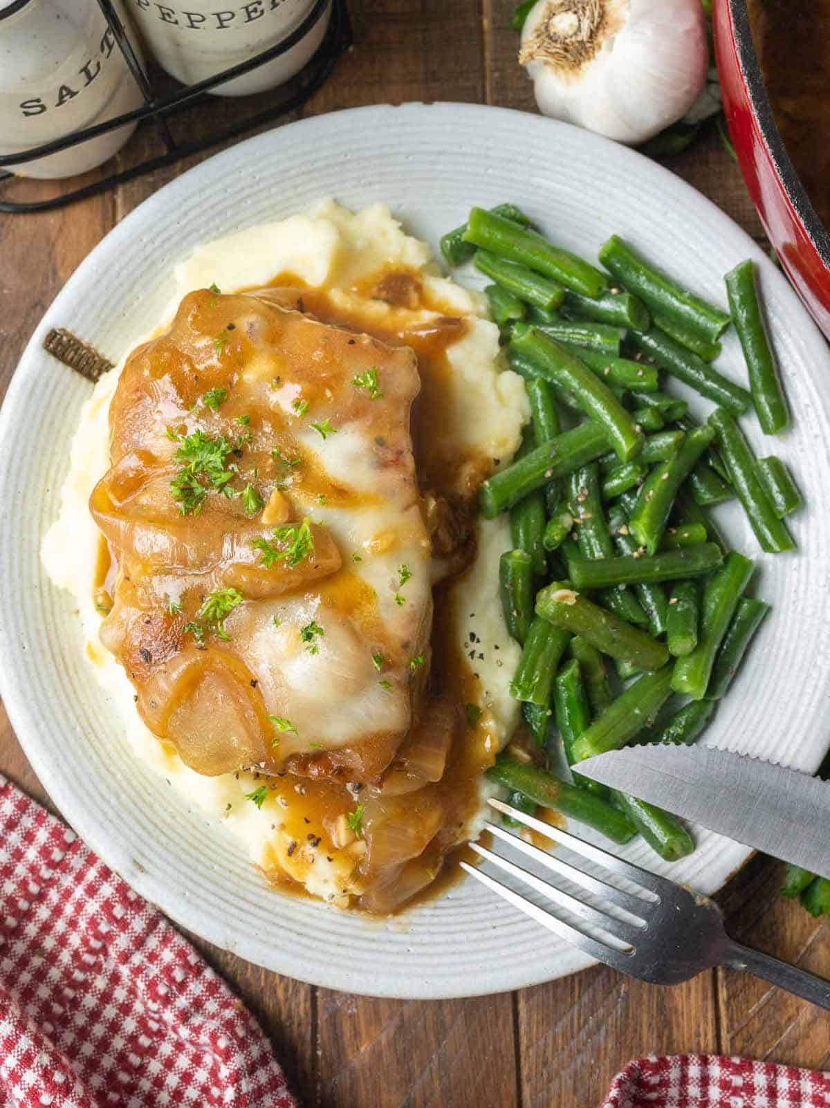 French onion pork chop on a pile of mashed potatoes.