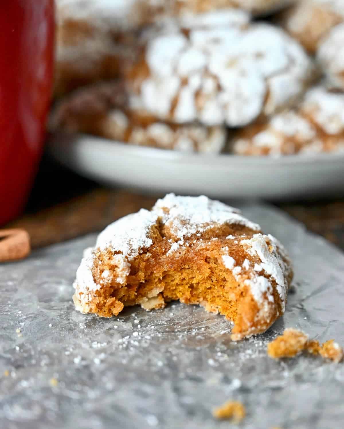 Pumpkin crinkle cooie with a bite out of it on a piece of parchment paper.