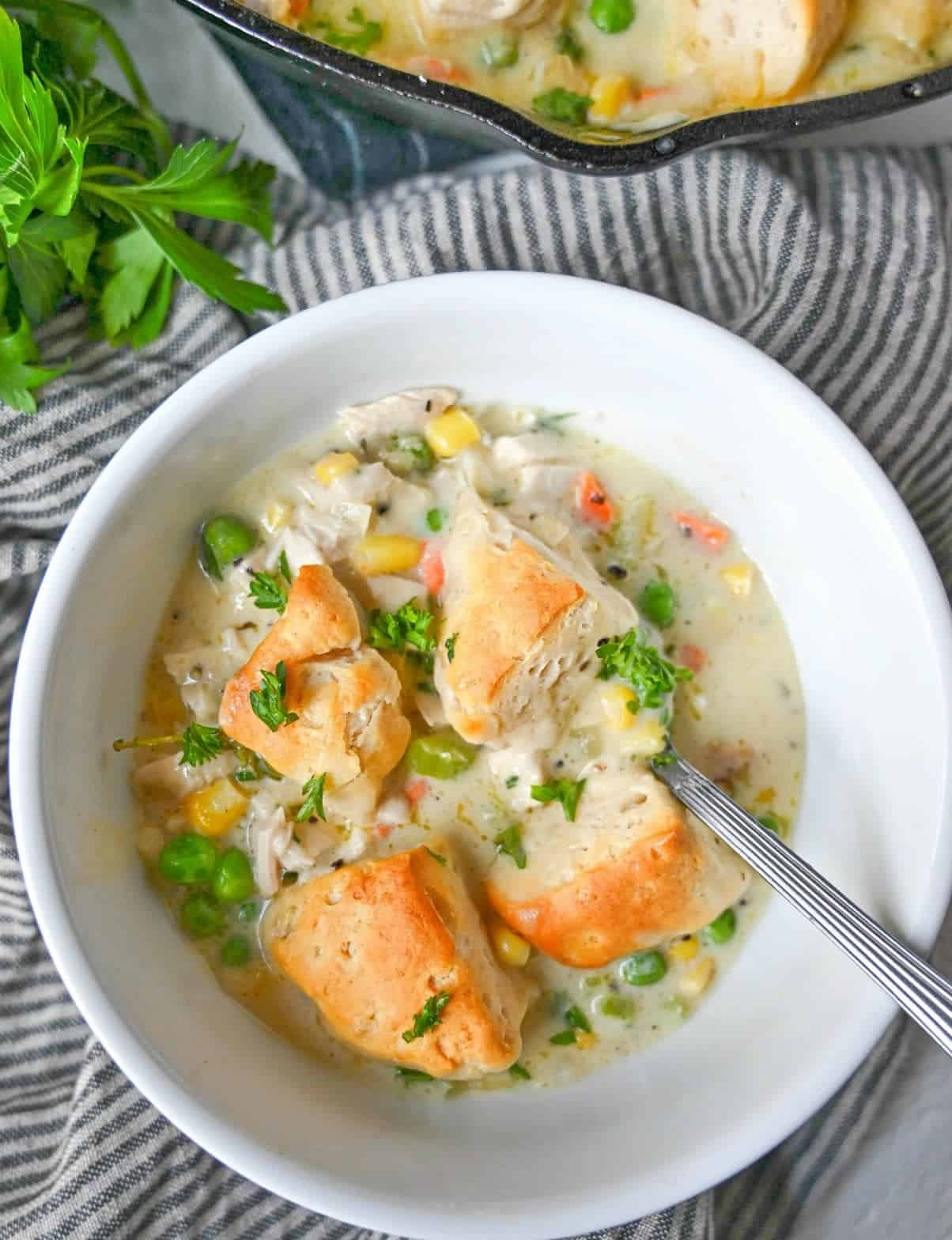 skillet chicken and biscuit pot pie in a white bowl and a spoon.