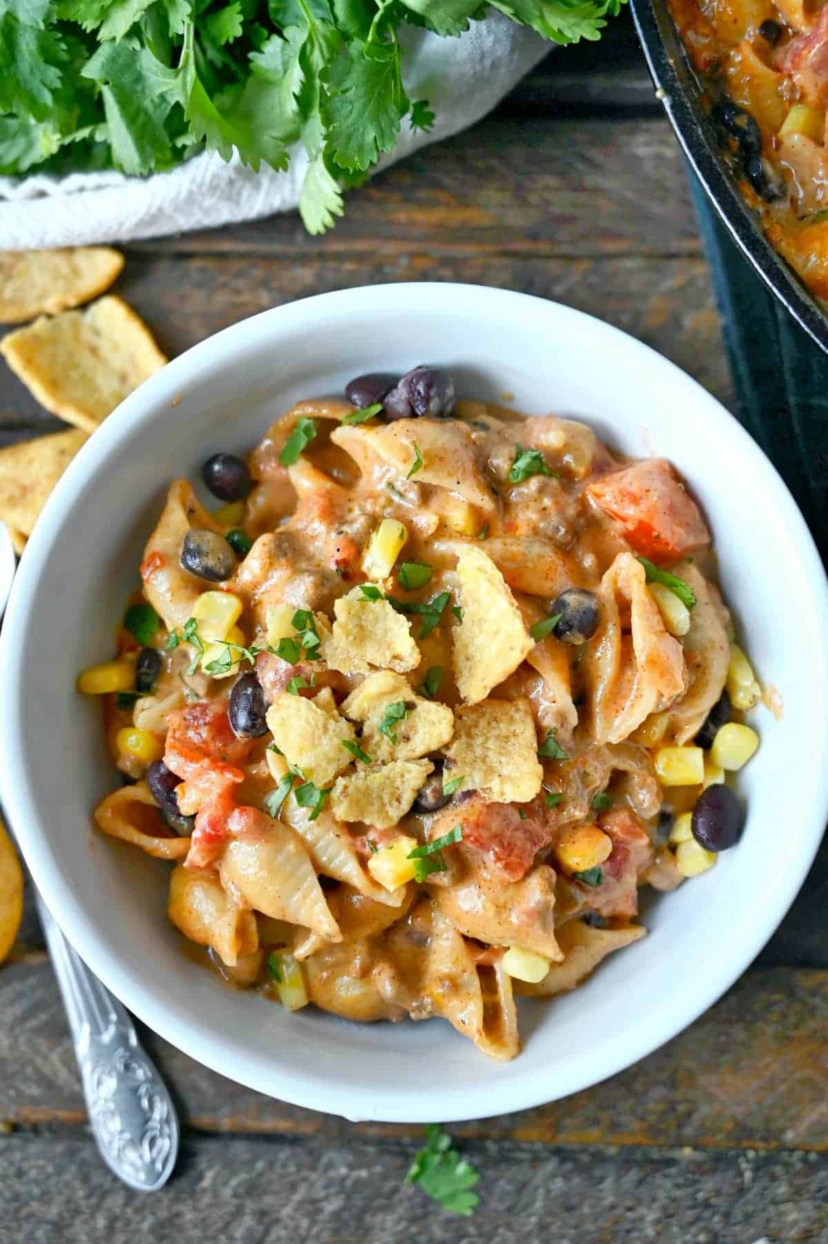 Taco pasta in a white bowl with crushed fritos on top.