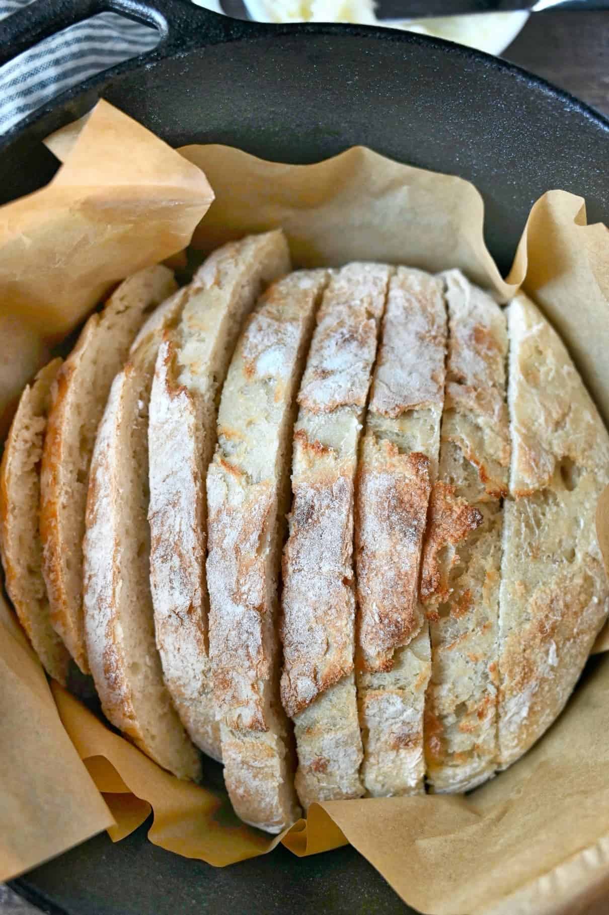 A loaf of artisan bread in a dutch oven sliced. 