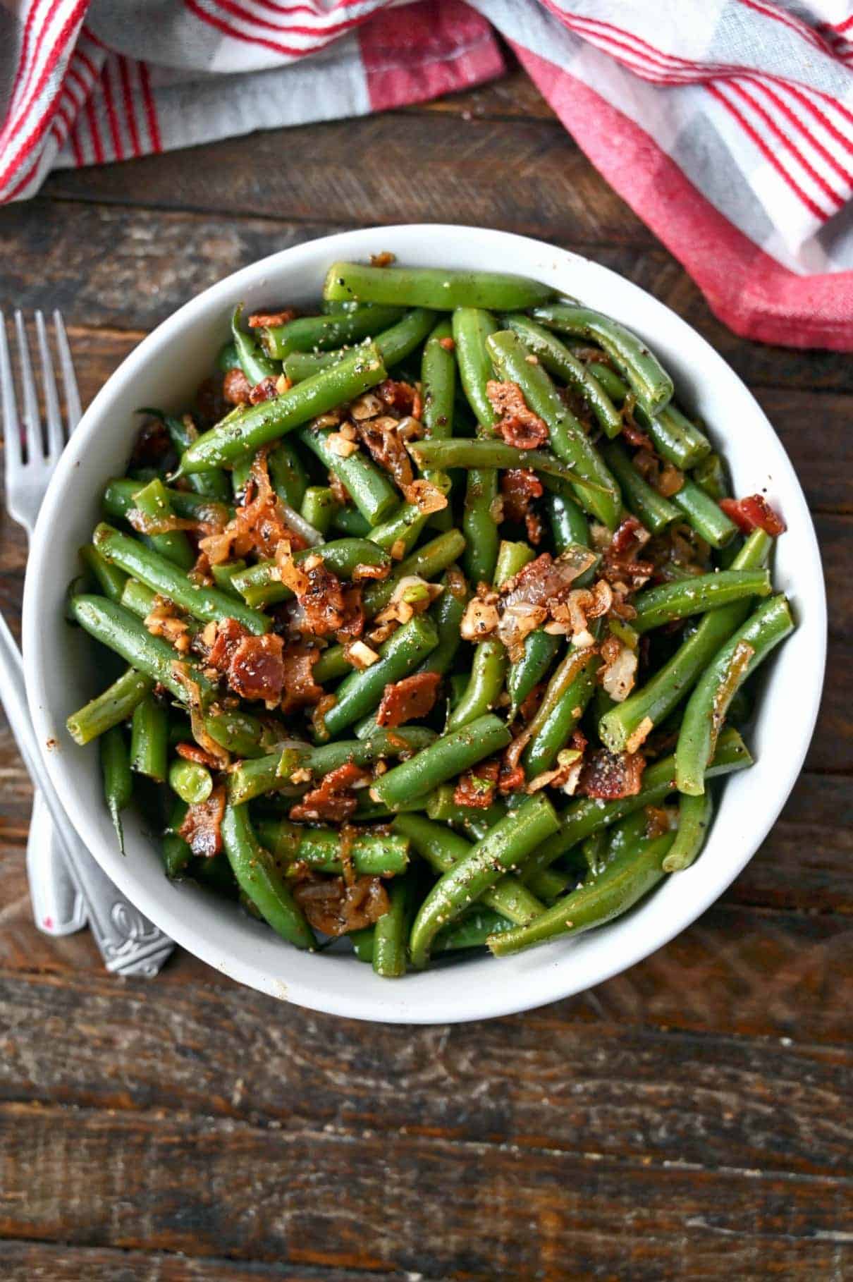 Green beans with bacon and caramelized onion in a white bowl.