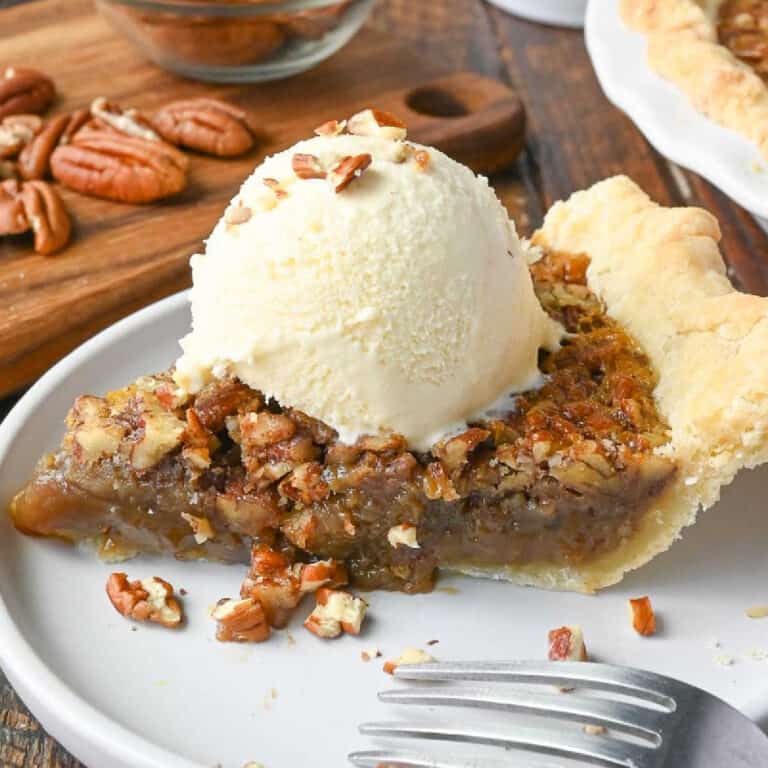 Maple pecan pie on a plate with ice cream.