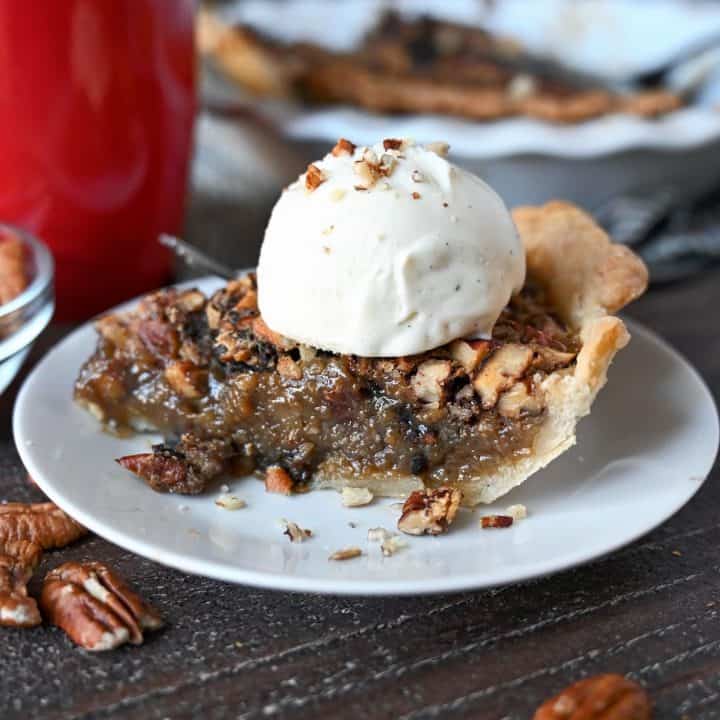 A slice of maple pecan pie with a scoop of vanille ice cream on top.