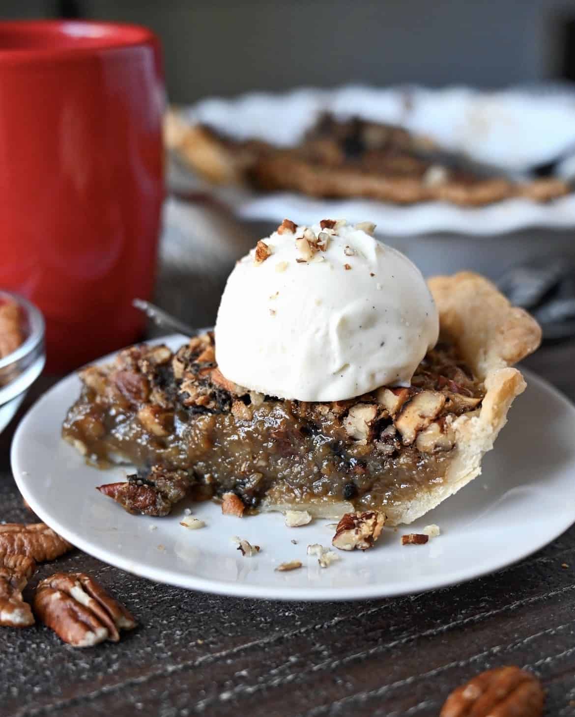 A slice of maple pecan pie with a scoop of vanille ice cream on top.