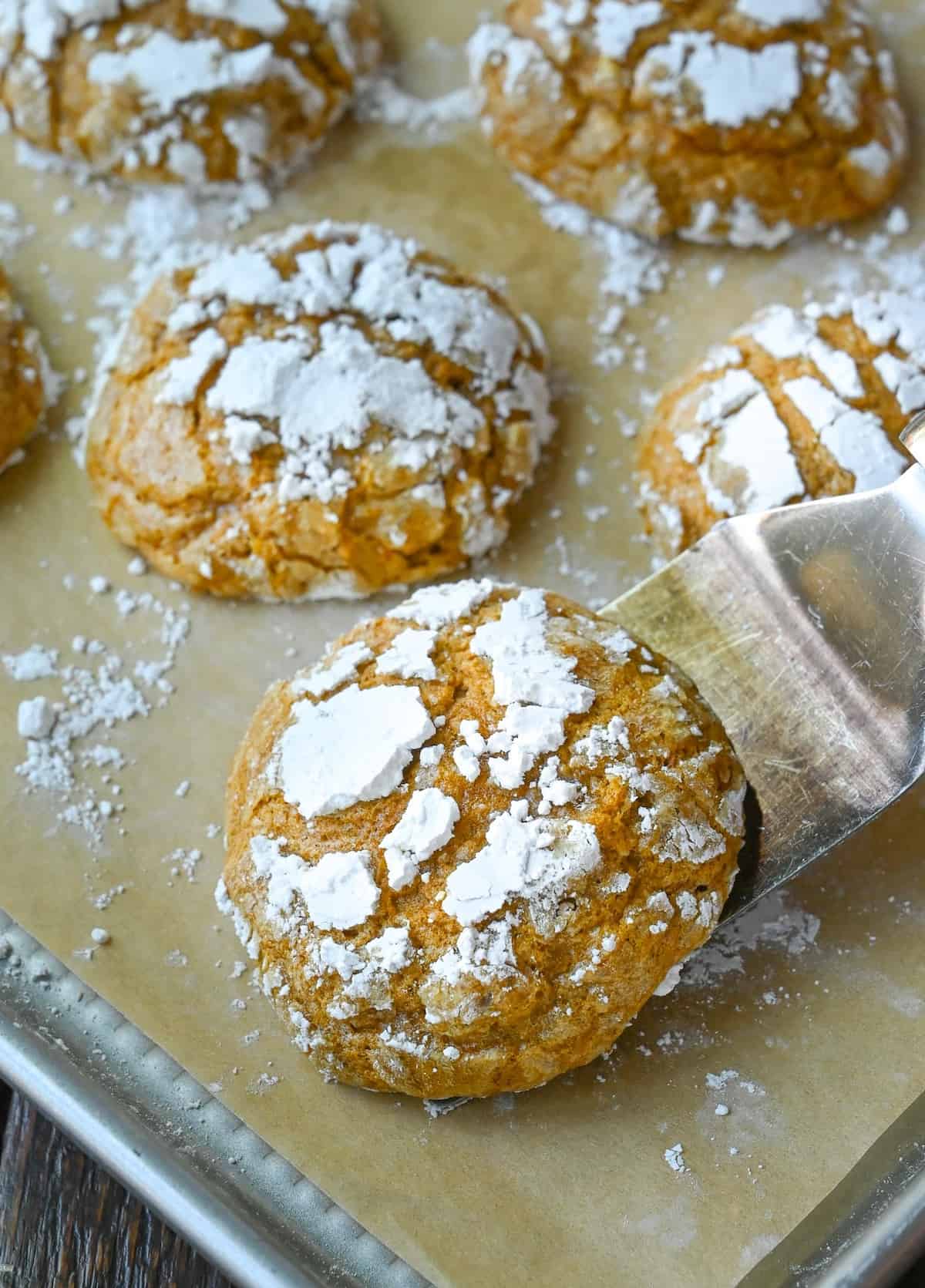 A spatula picking up a baked pumpkin crinkle cookie.