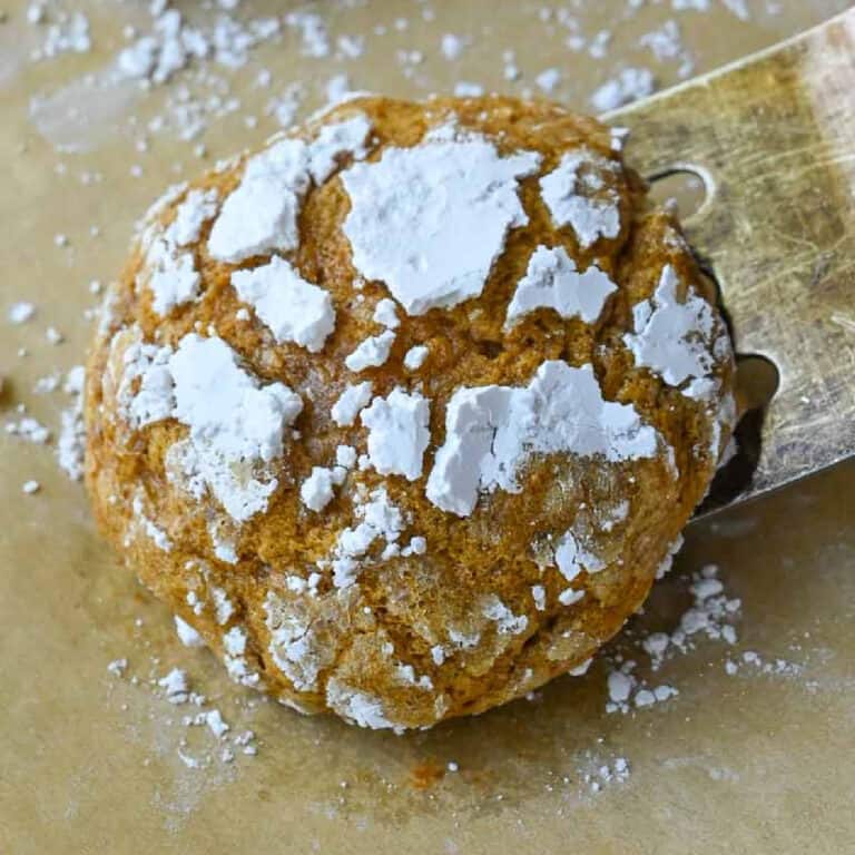 A spatula picking up a baked pumpkin crinkle cookie.