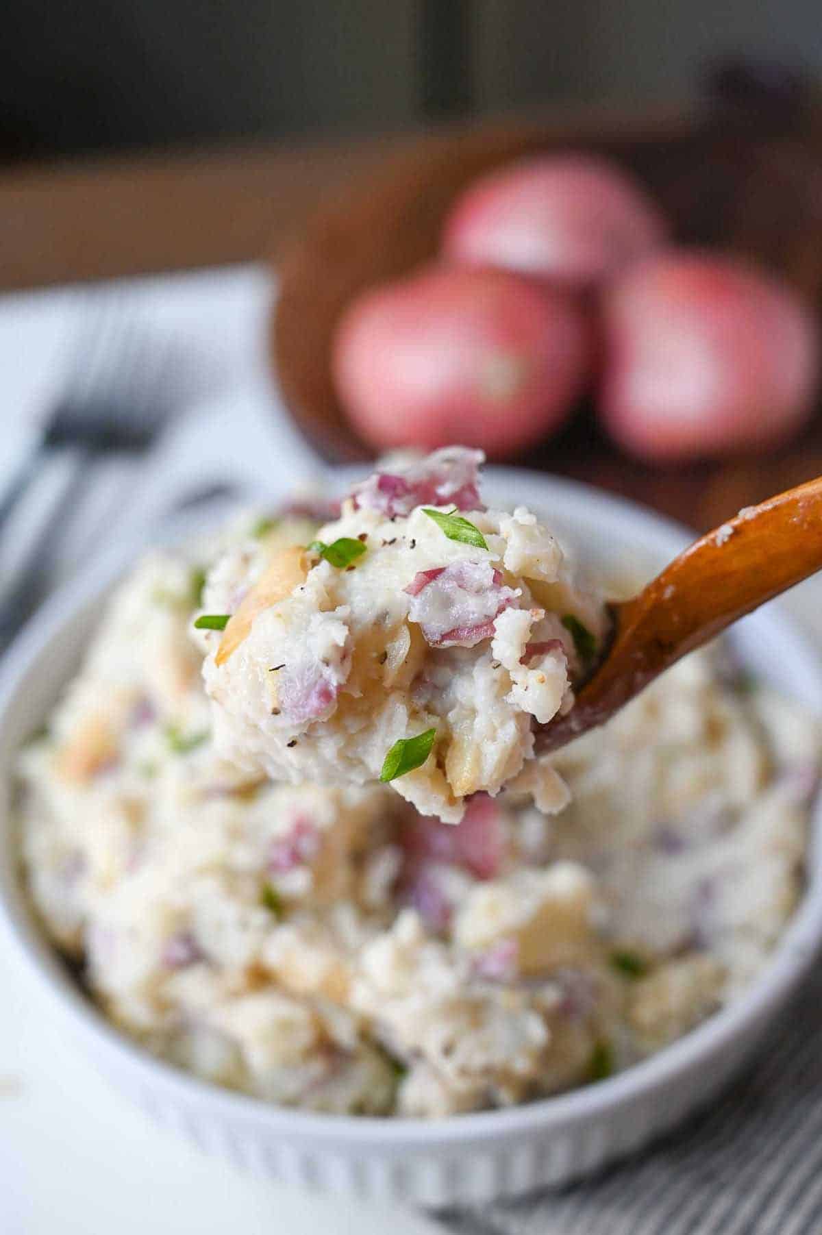 A wooden spoon scooping up a bite of mashed potatoes.