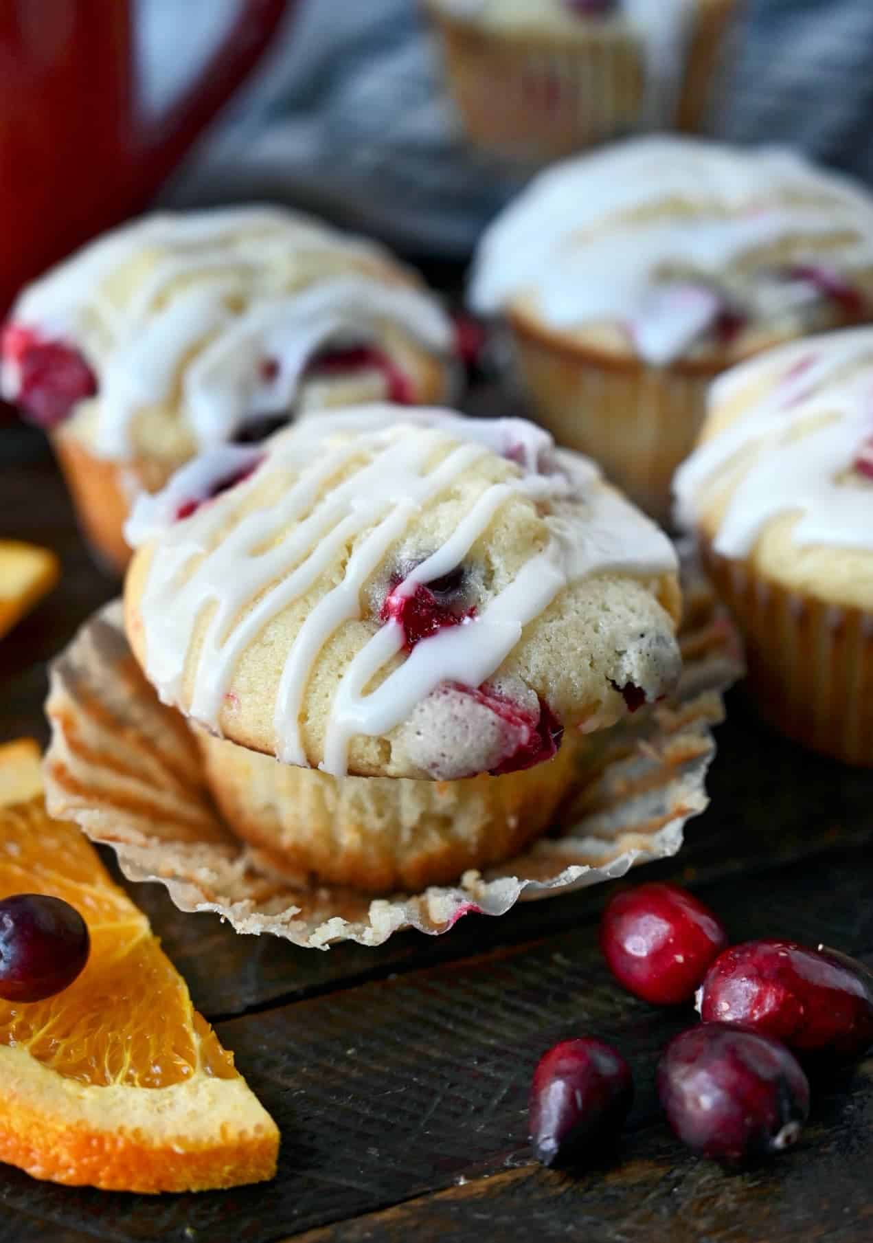 cranberry orange muffin with the wrapper pulled down and orange slices on the side.