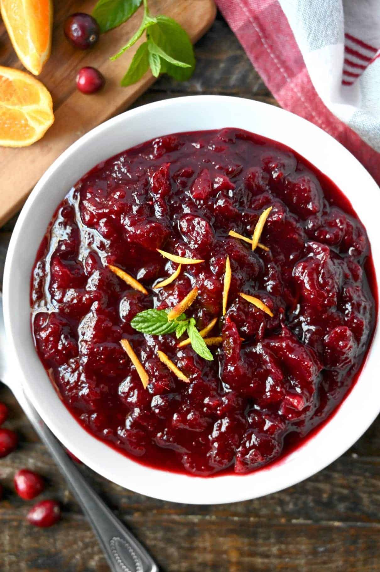 A bowl of fresh cranberry sauce with a sprig of mint in the center.