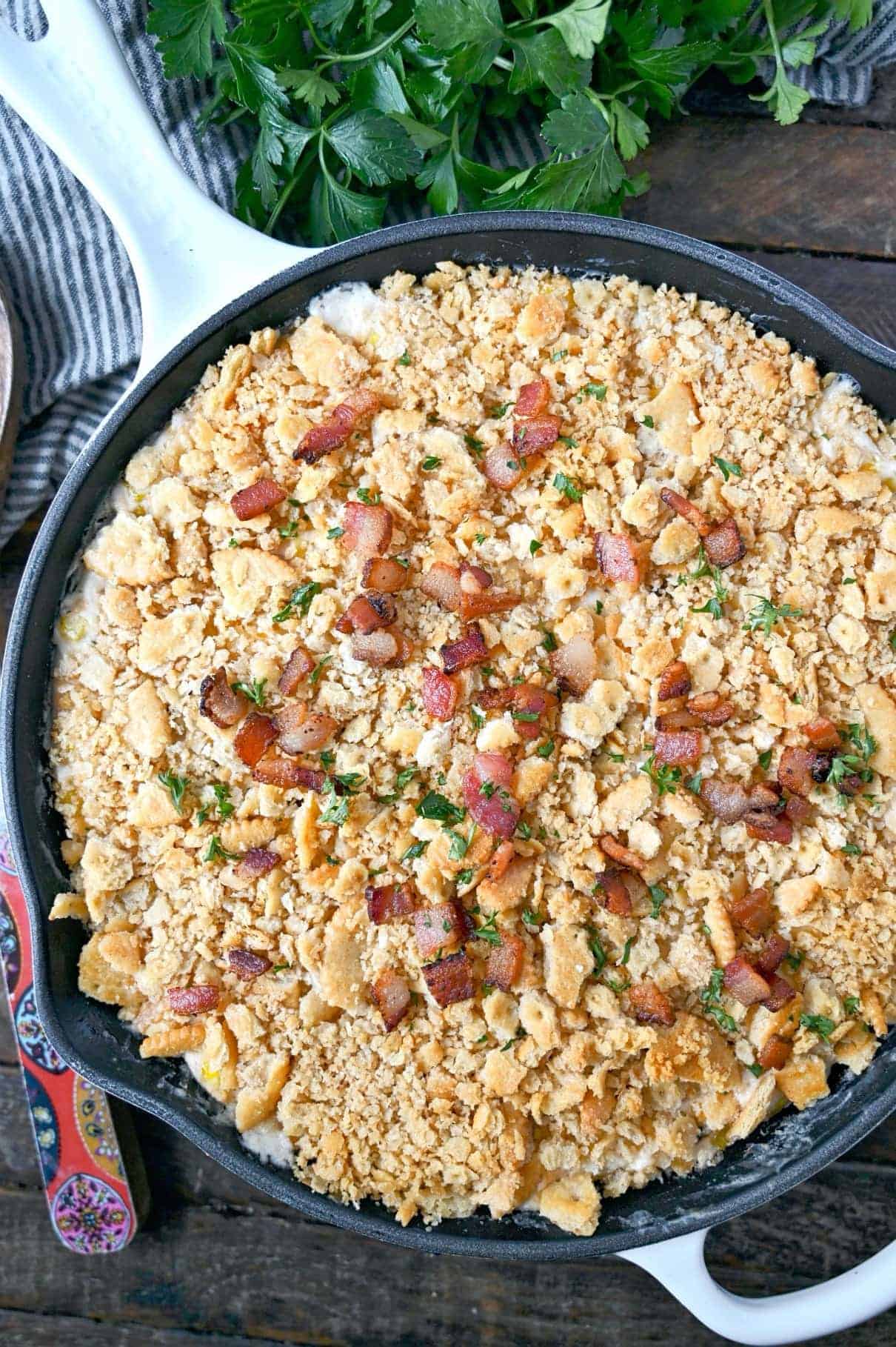 Cheesy corn casserole with a ritz cracker topping in a cast iron skillet.