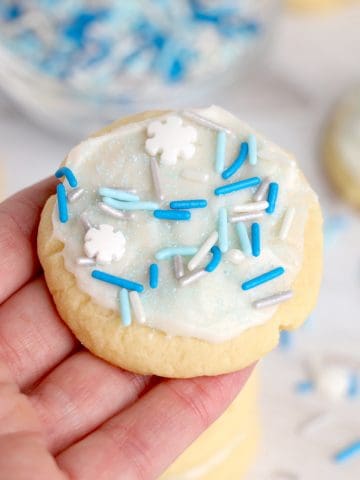 Meltaway cookie with blue Christmas sprinkles on top being held in hand.