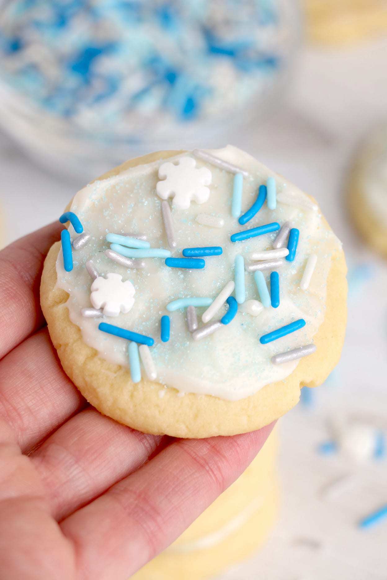 Meltaway cookie with blue Christmas sprinkles on top being held in hand.
