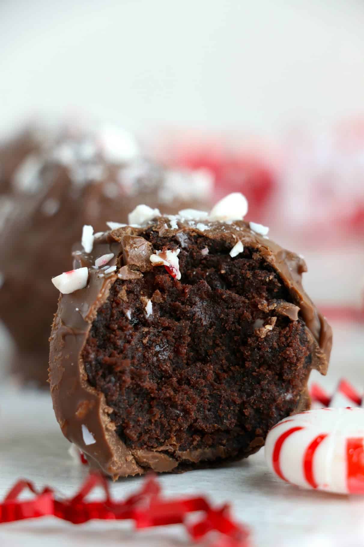 Peppermint chocolate cake truffle with a bite out of it and a peppermint candy on the side.