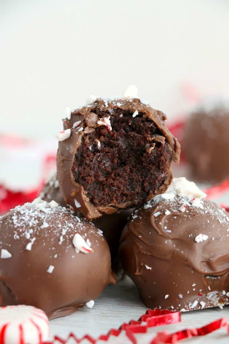 Three peppermint chcoclate cake truffles stacked on top of each other and a bite out of one.