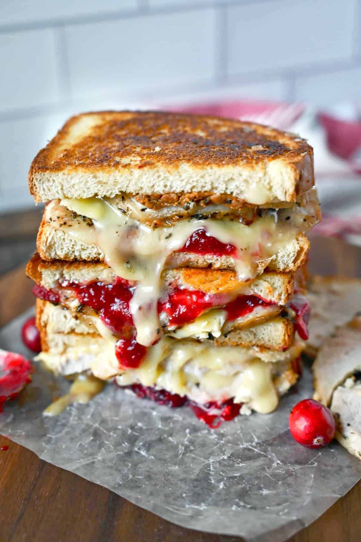 Three turkey cranberry brie sandwiches stacked on top of each other.