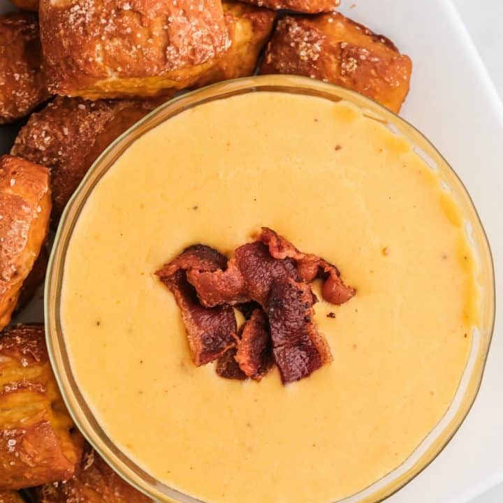 A bowl of beer cheese sauce with pretzel bites on the side.