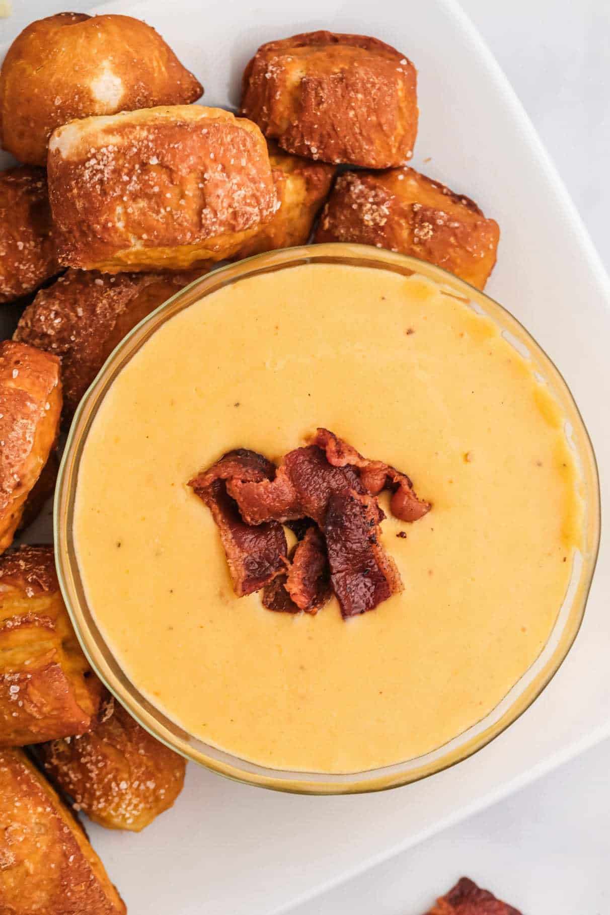 A bowl of beer cheese sauce with pretzel bites on the side. 