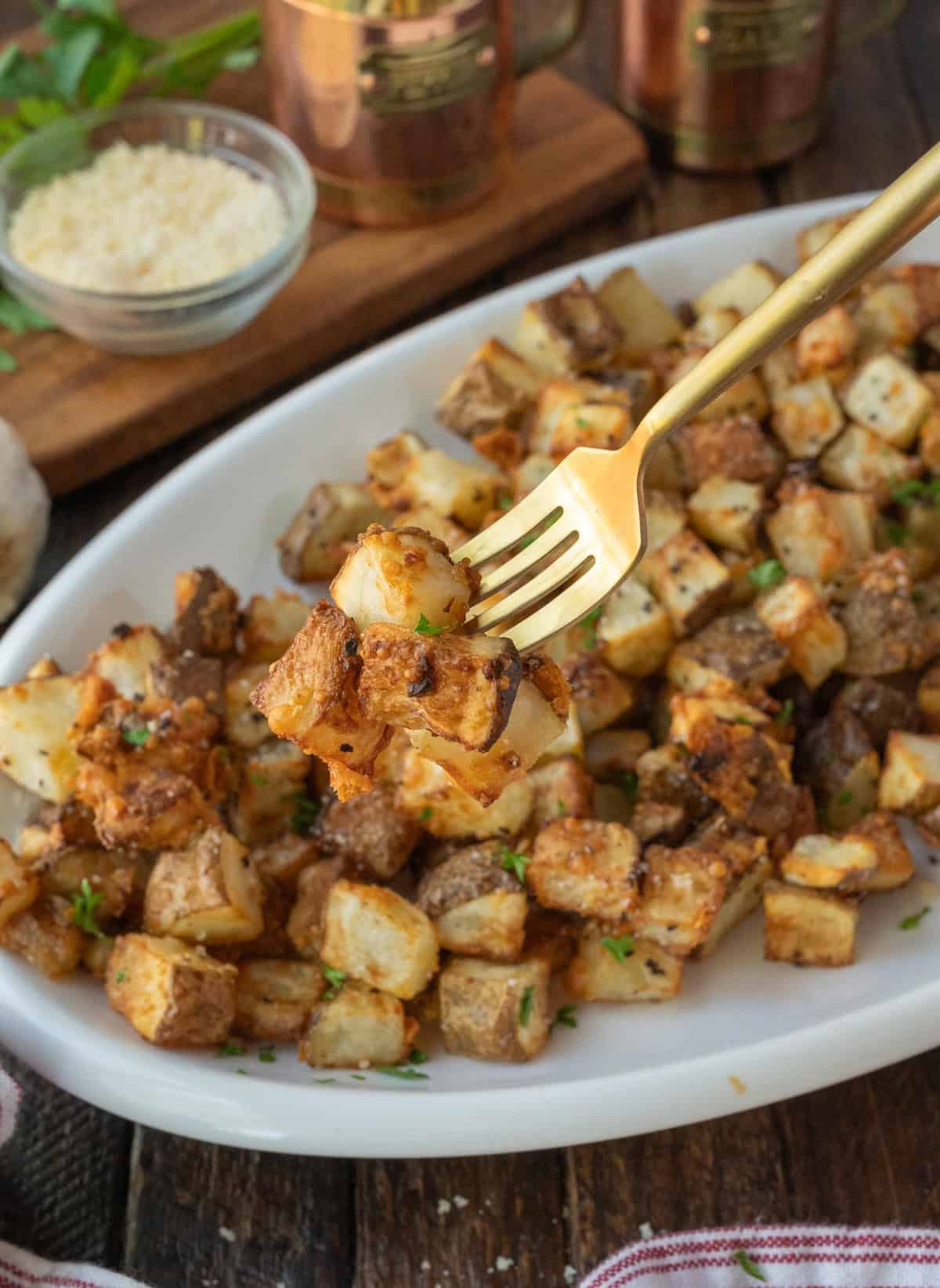 Air fryer potatoes on a platter with a fork picking up a bite.