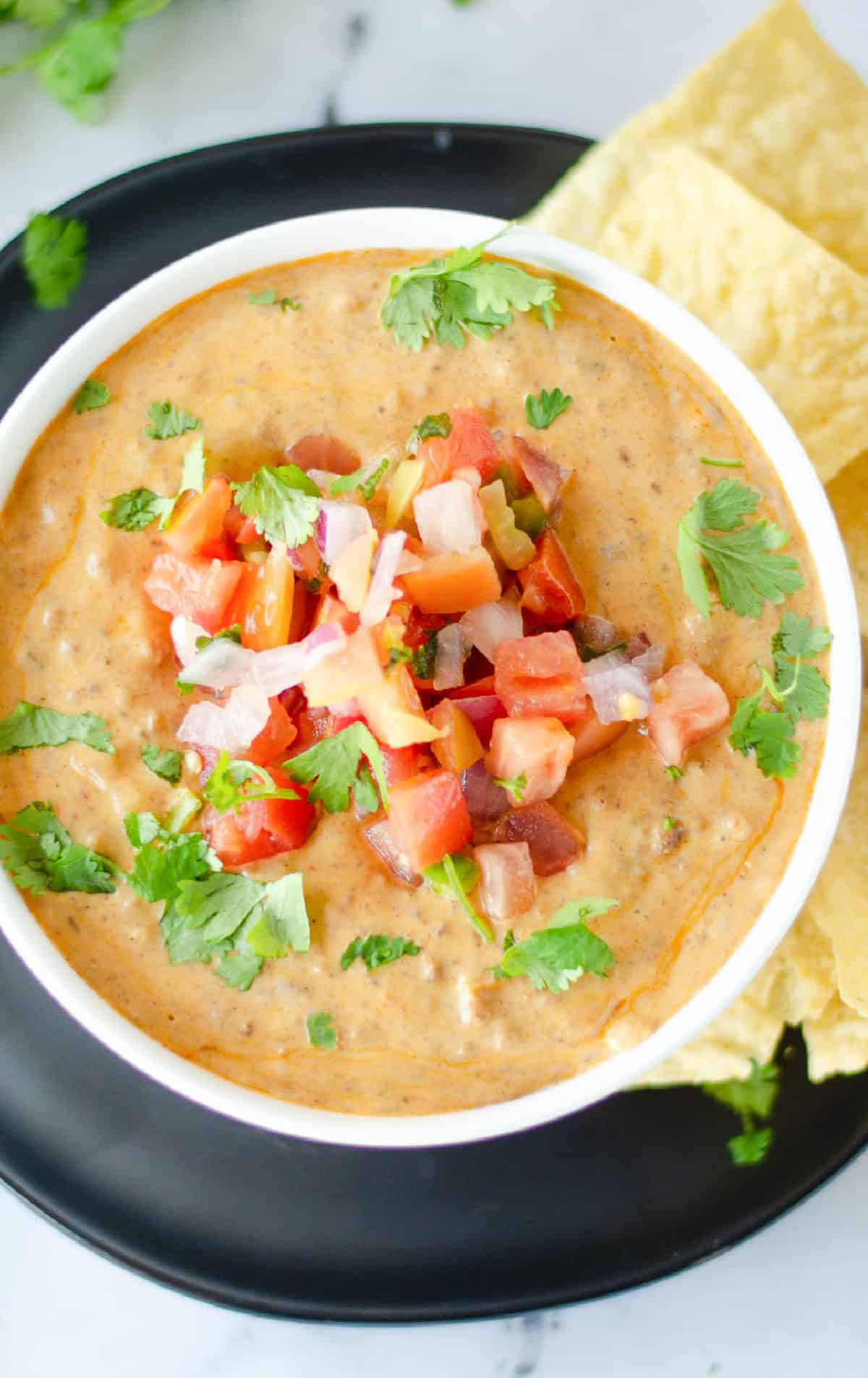 A bowl of queso with pico de gallo on top.