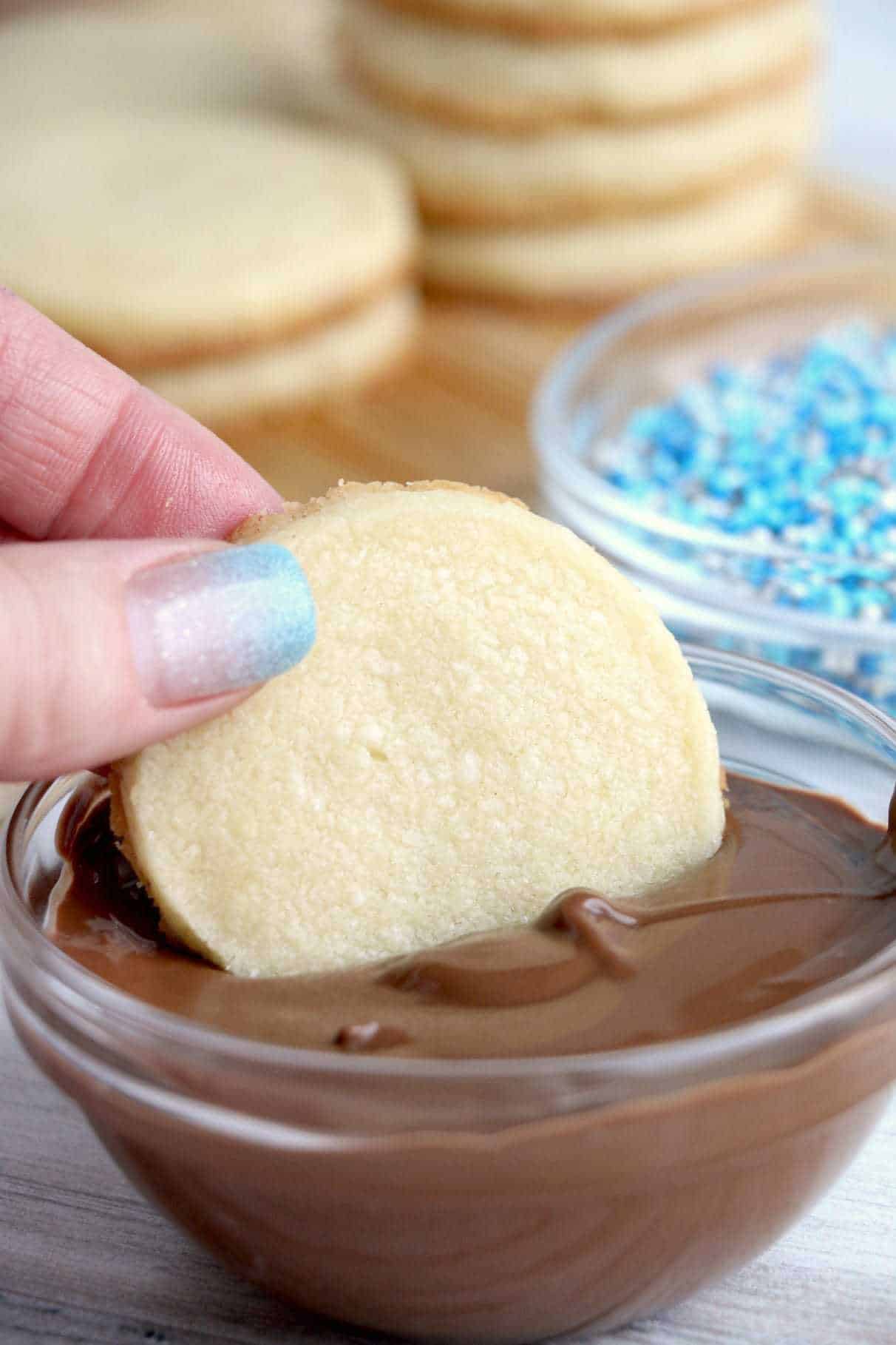 Butter cookie being dipped into chocolate.