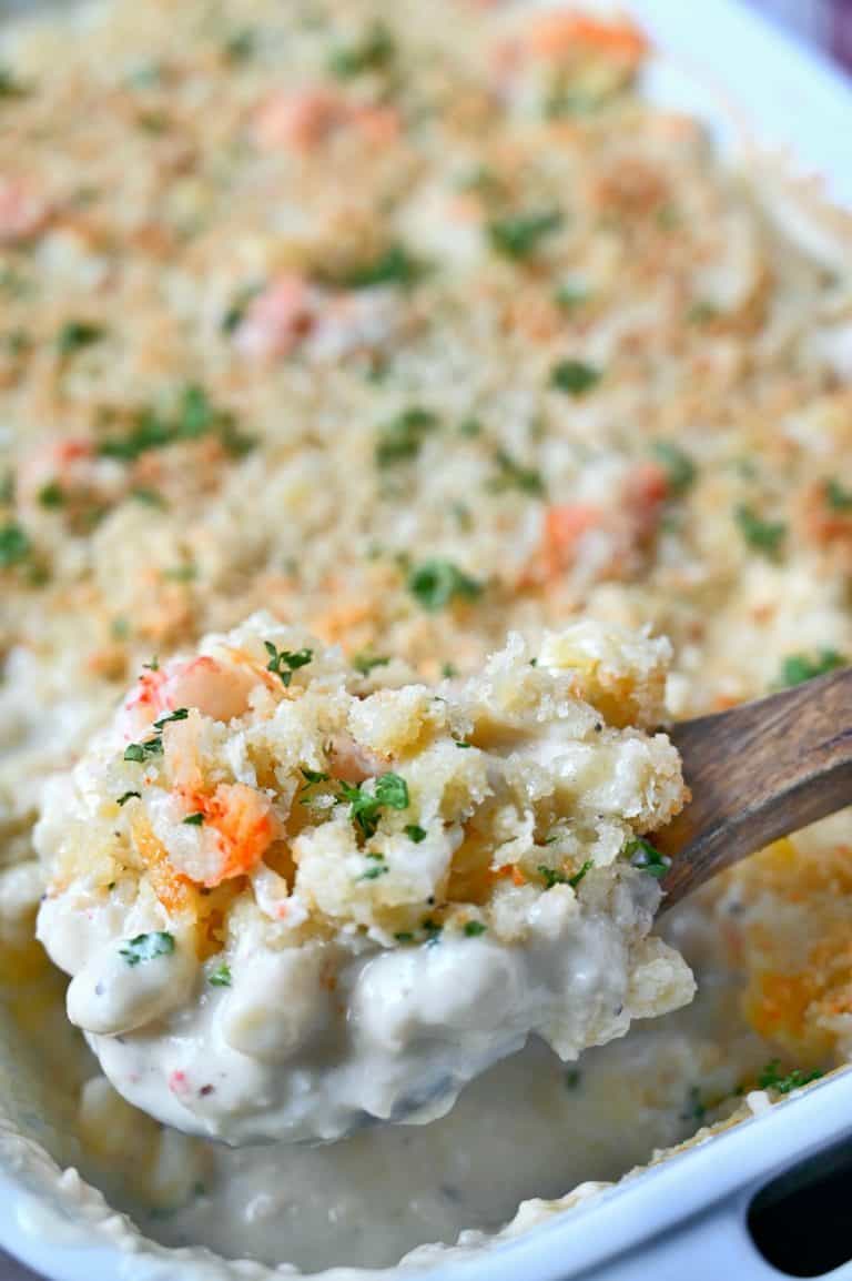 A wooden spoon scooping up some lobster mac and cheese.