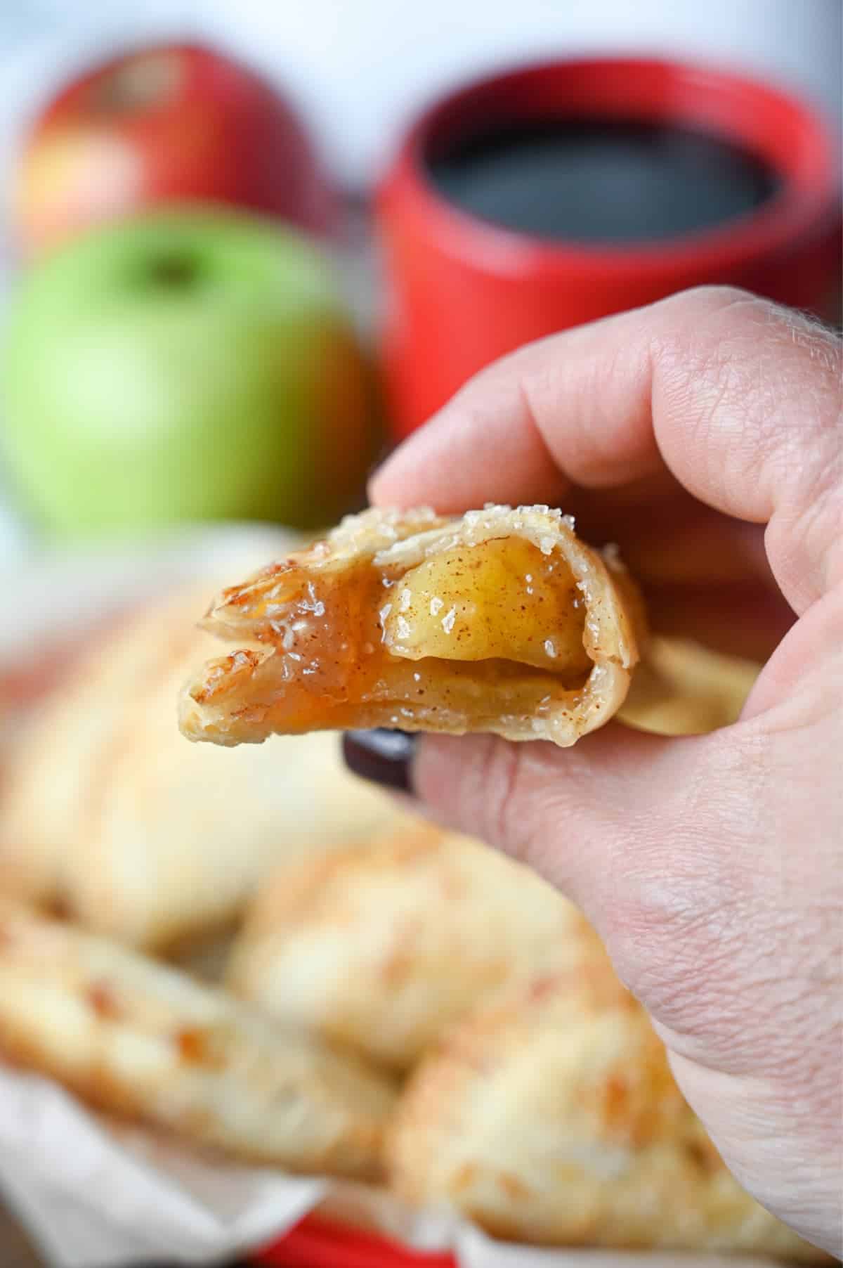 Air fryer apple hand pie with a bit out of it being held in a hand.