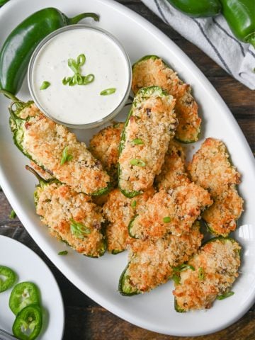 Jalapeno poppers on a white oval plate with a side of ranch dressing.