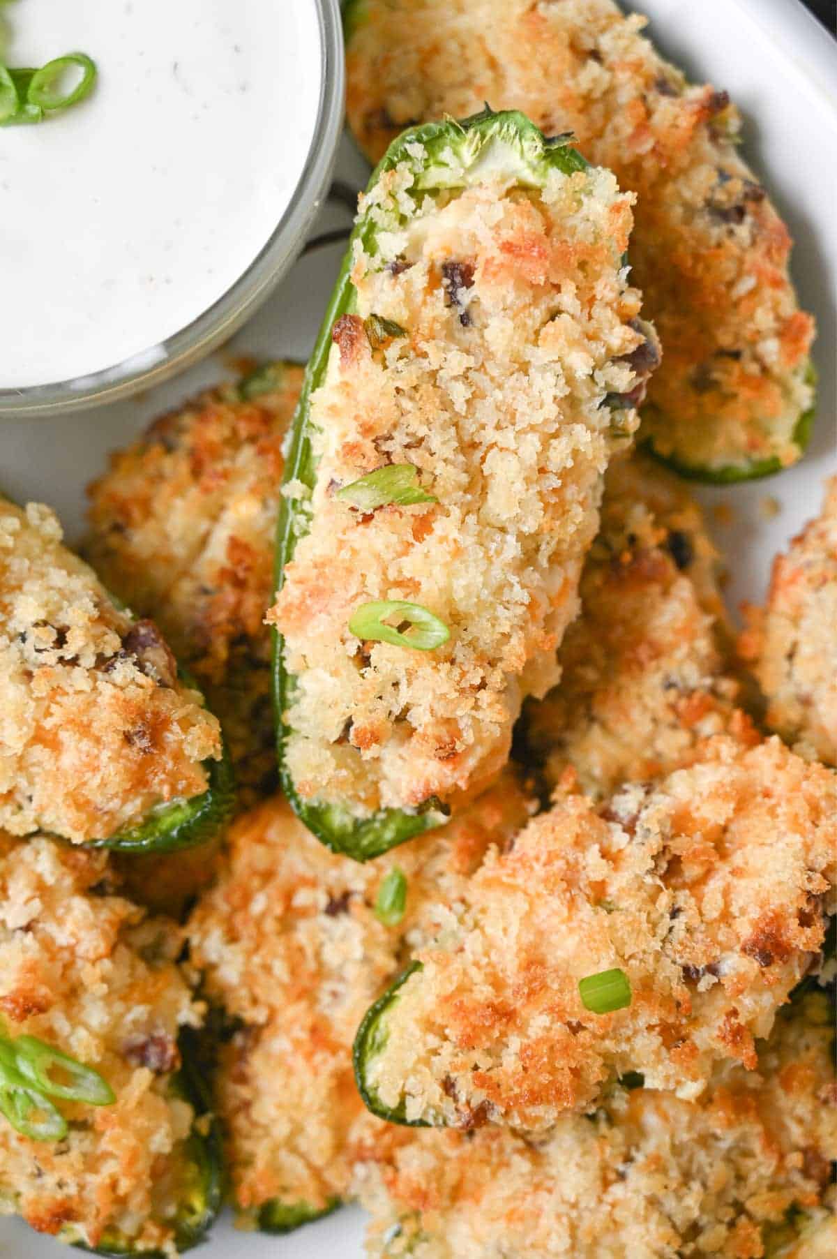 Close up photo of jalapeno poppers piled on a white plate.