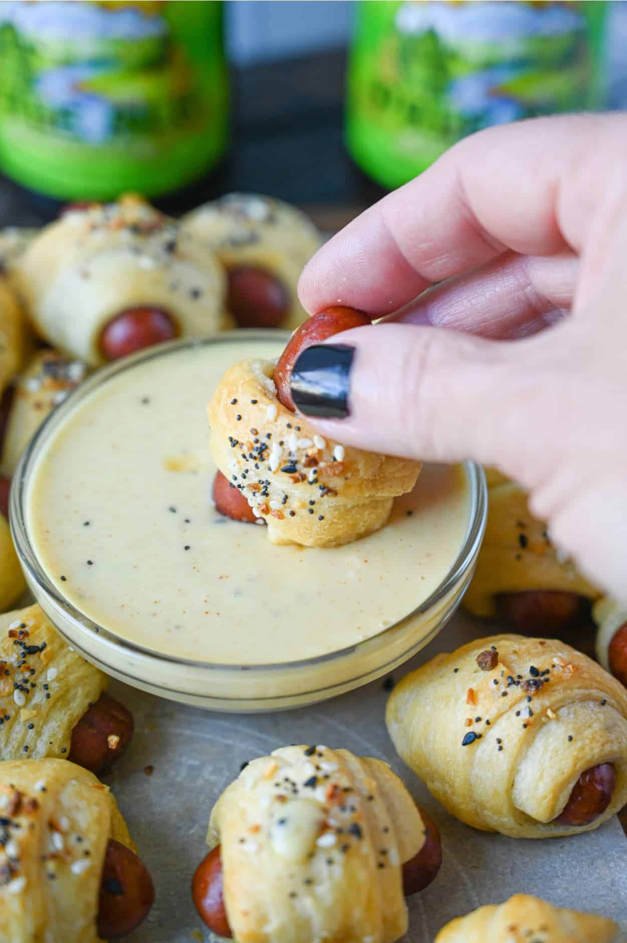 Pig in blanket being dipped into honey mustard. 