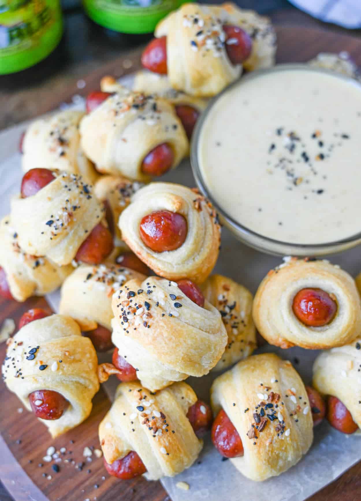 Pigs in a blanket piled on tope of each other with a side of honey mustard in a small dish.