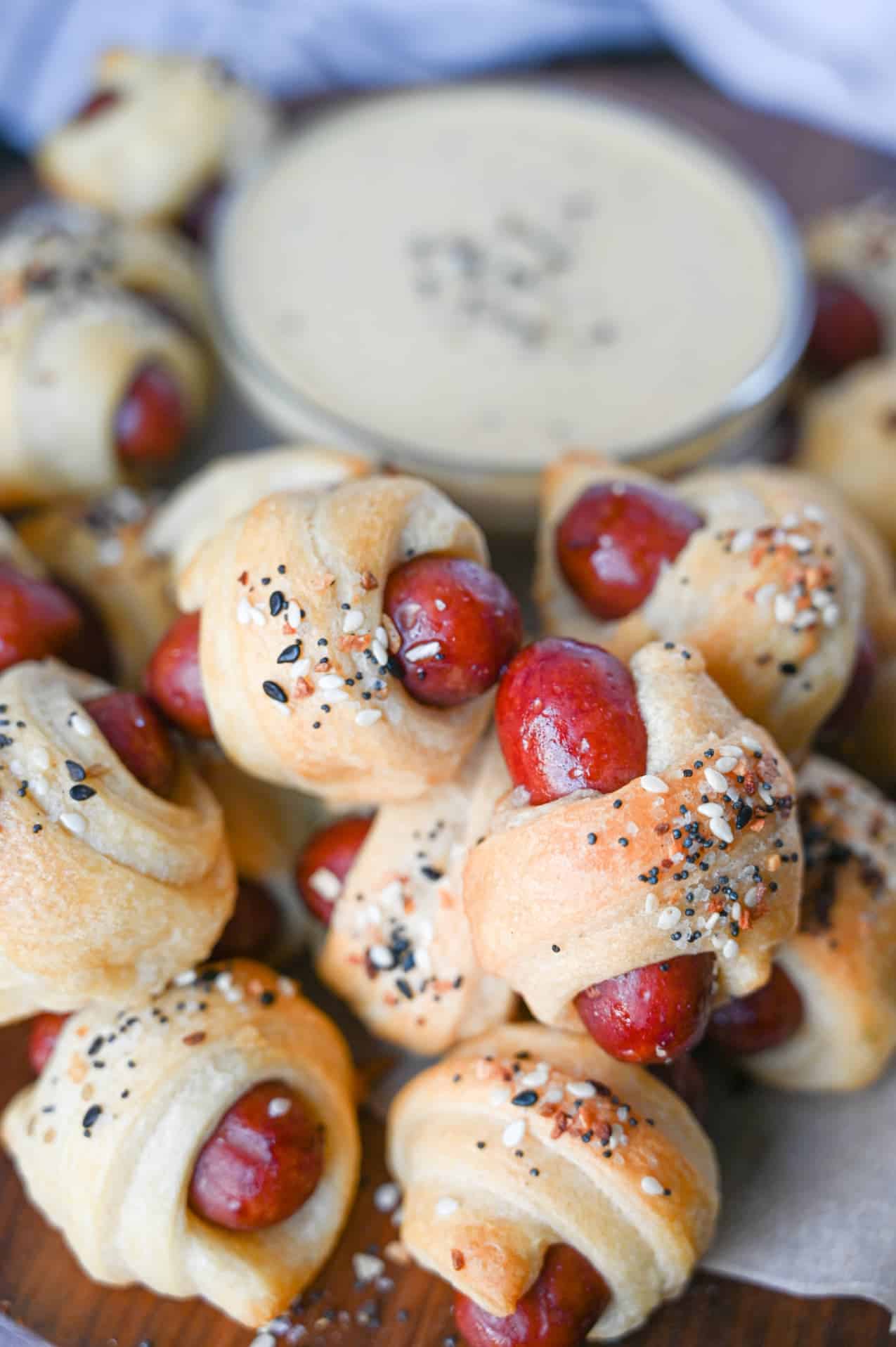 Pigs in a blanket piled on tope of each other with honey mustard in the background.